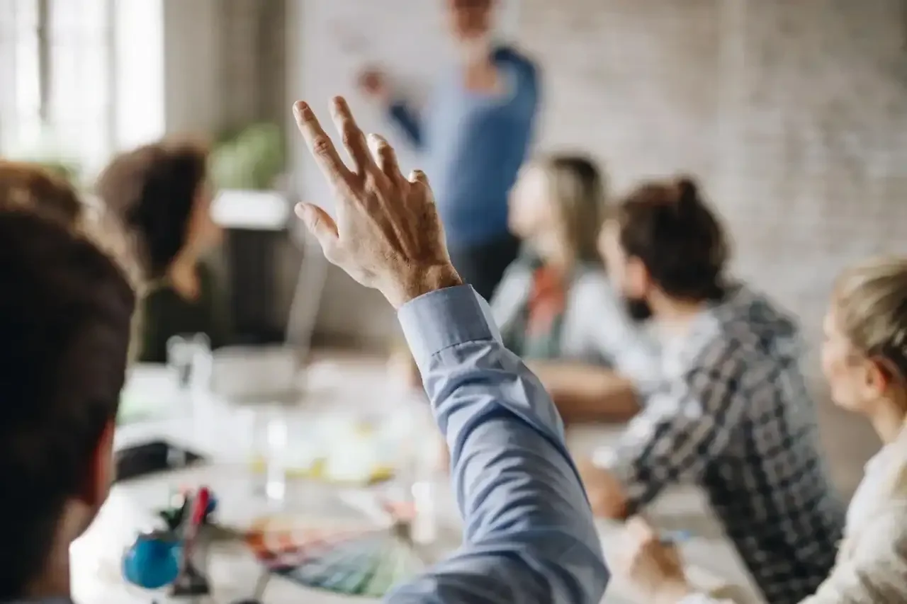 A raised hand in a team meeting suggesting a question
